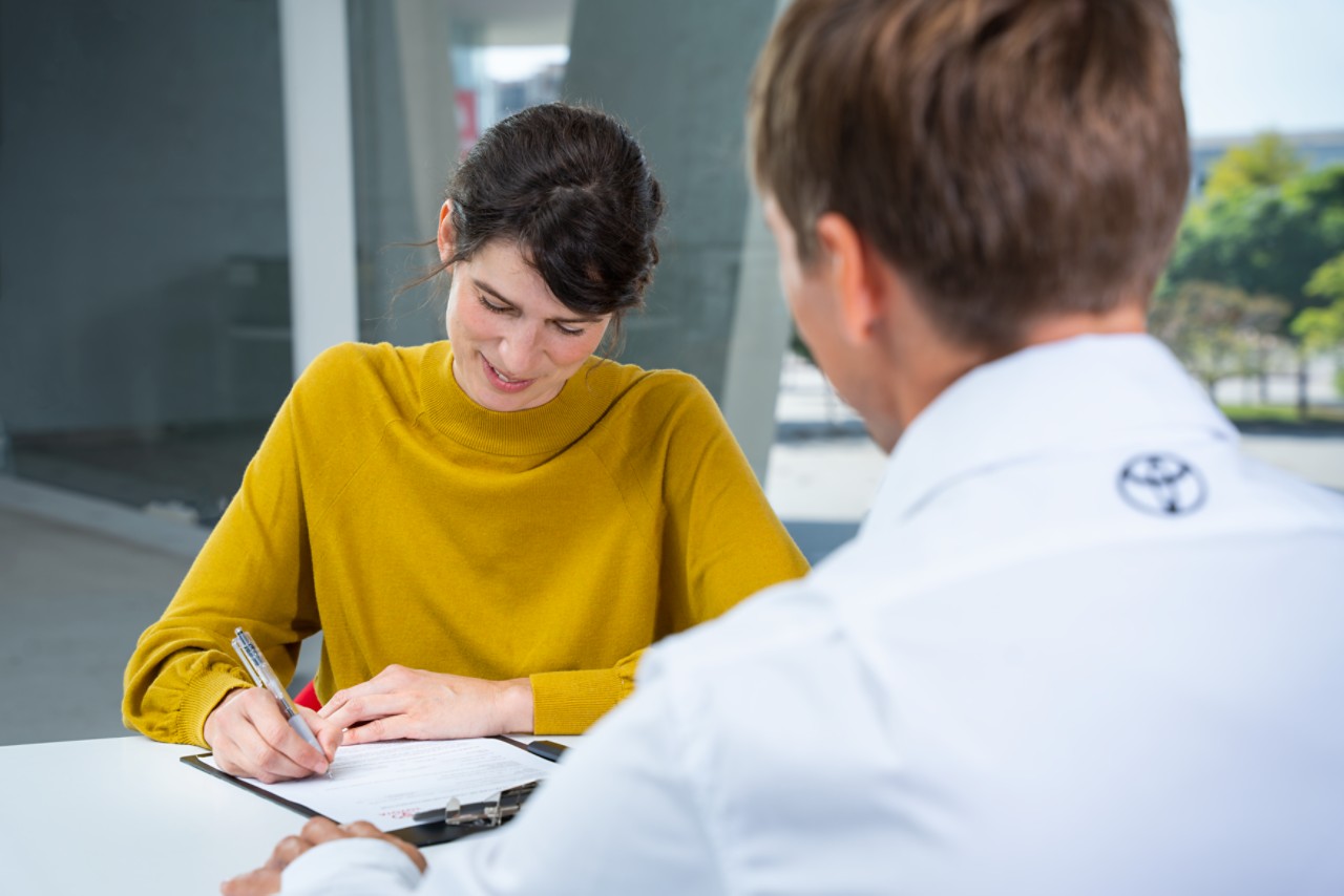 Signature d'un contrat de location avec option d'achat par une cliente Toyota